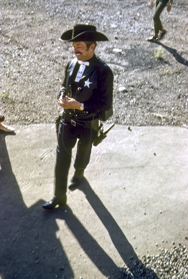Free image of Man dressed as a sheriff, walking with a gun.