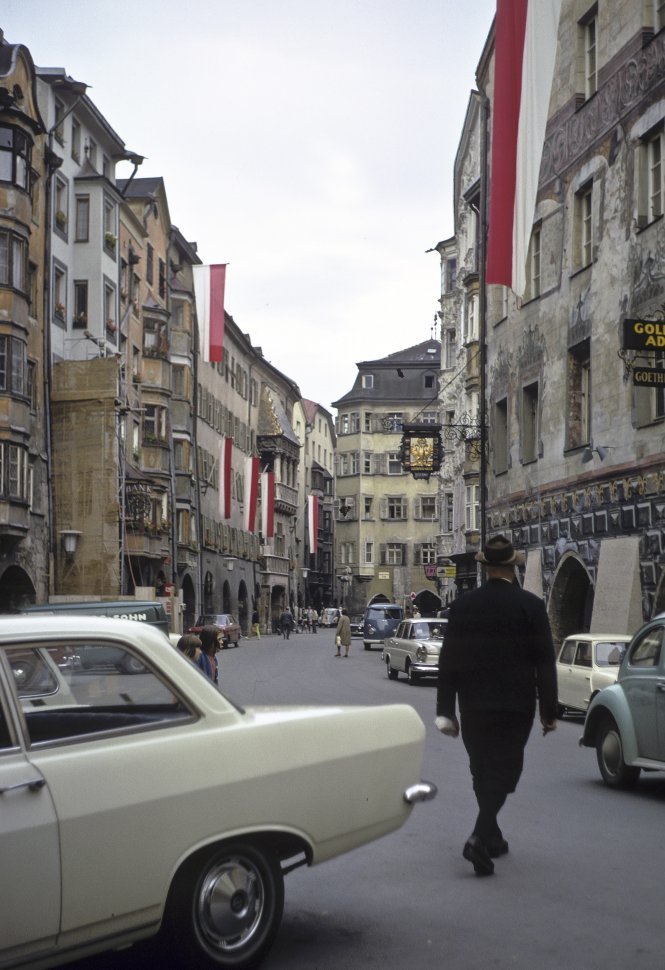 Free image of Man walking down a small street under flags, circa 1968, Vienna, Austria