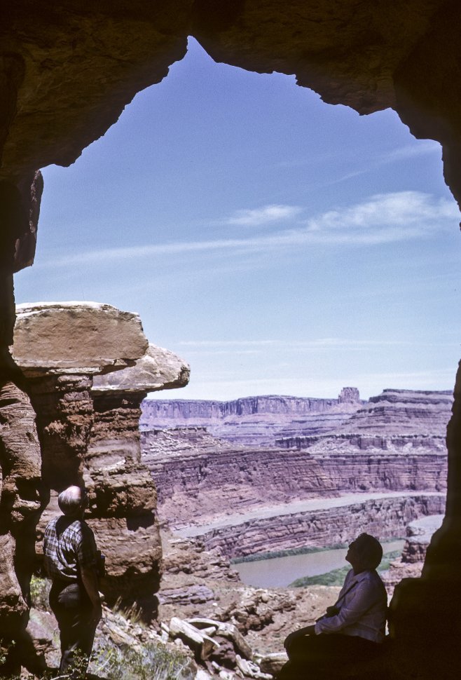 Free image of Two people standing under a stone arch, looking out over a river and canyon, Arizona, USA