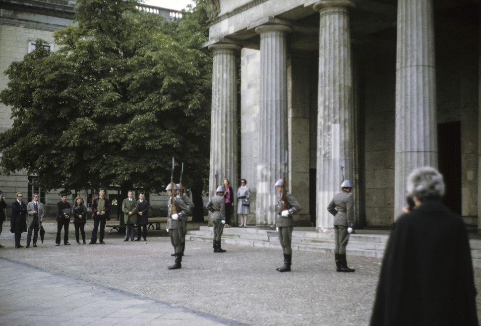 Free image of Group of people watching soldiers in formation in front of large columns.