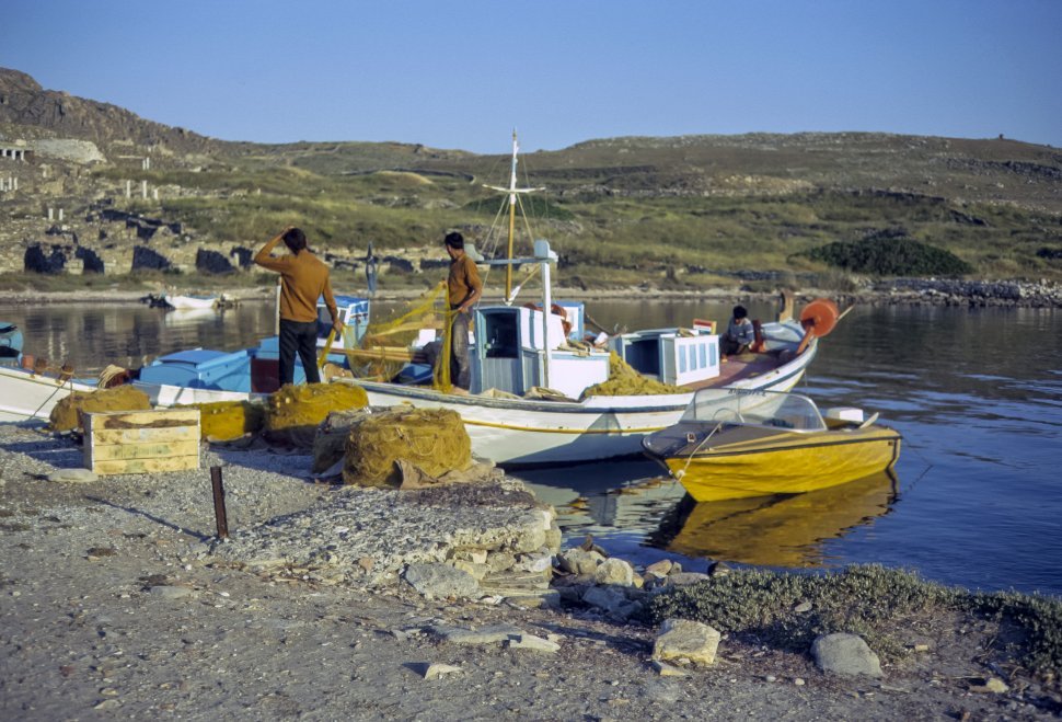 Free image of Two men and a child on a fishing boat loading equipment.