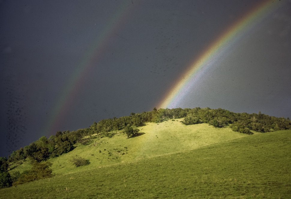 Free image of Landscape image of a double rainbow above a hillside.