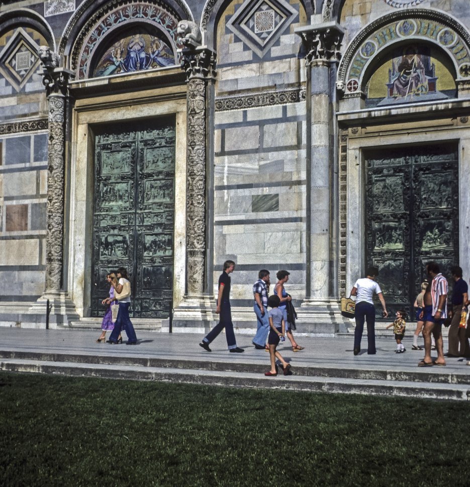 Free image of Tourists walking in front of a beautiful tiled building with murals.