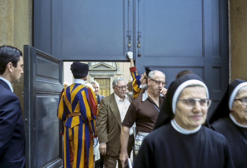 Free image of Group of nuns and gentlemen walking through a doorway.