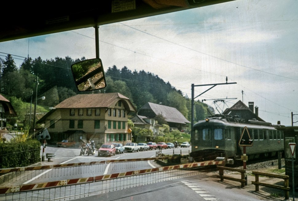 Free image of Train moving through a town at a rail crossing.
