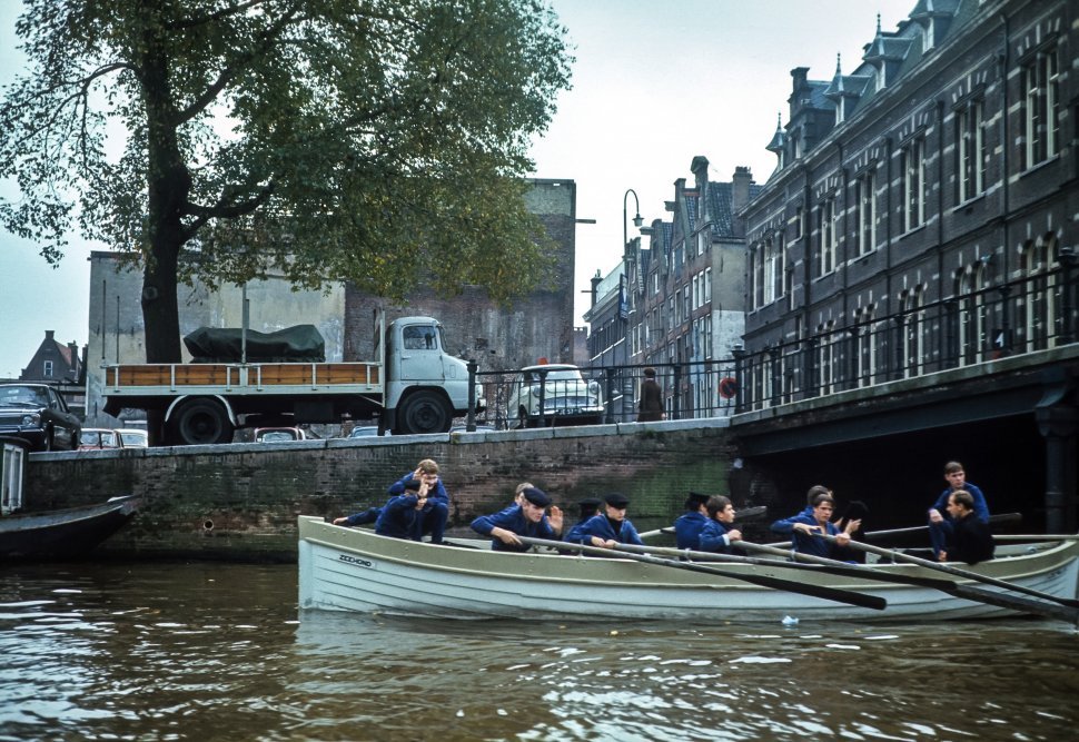 Free image of Crew of men rowing though a canal past buildings, Europe