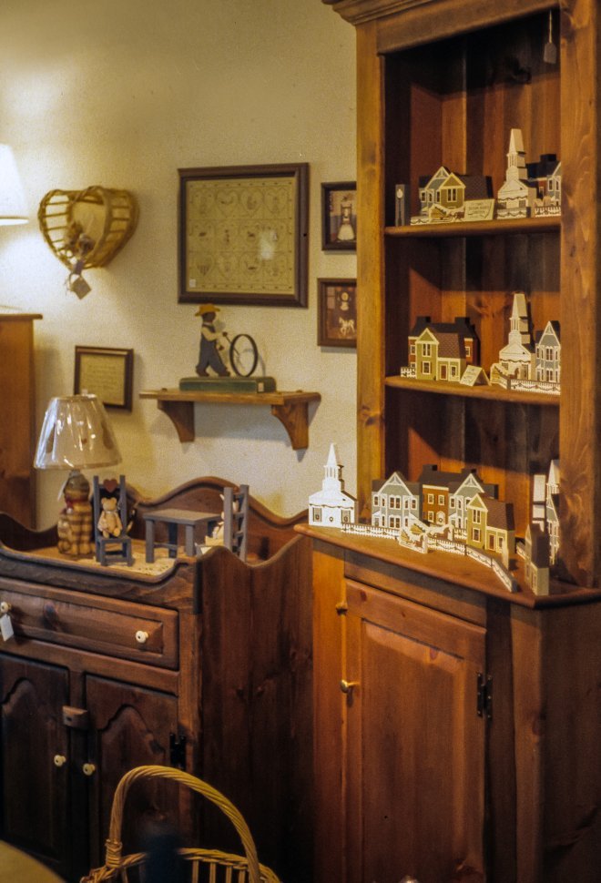 Free image of Wooden house carvings displayed on shelves of a wooden cabinet.
