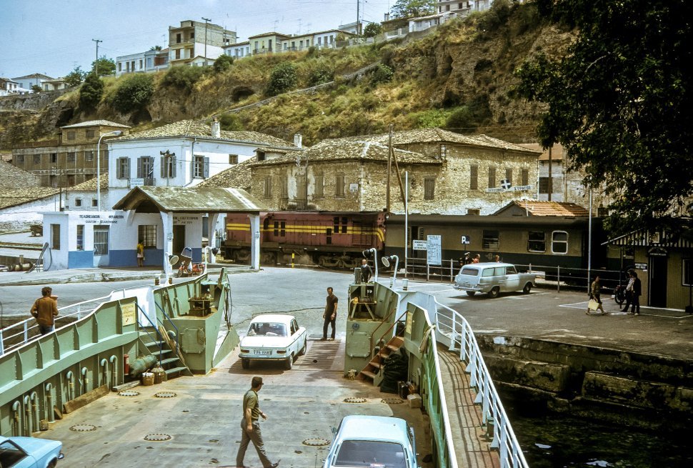 Free image of Cars driving off a ferry boat into village.