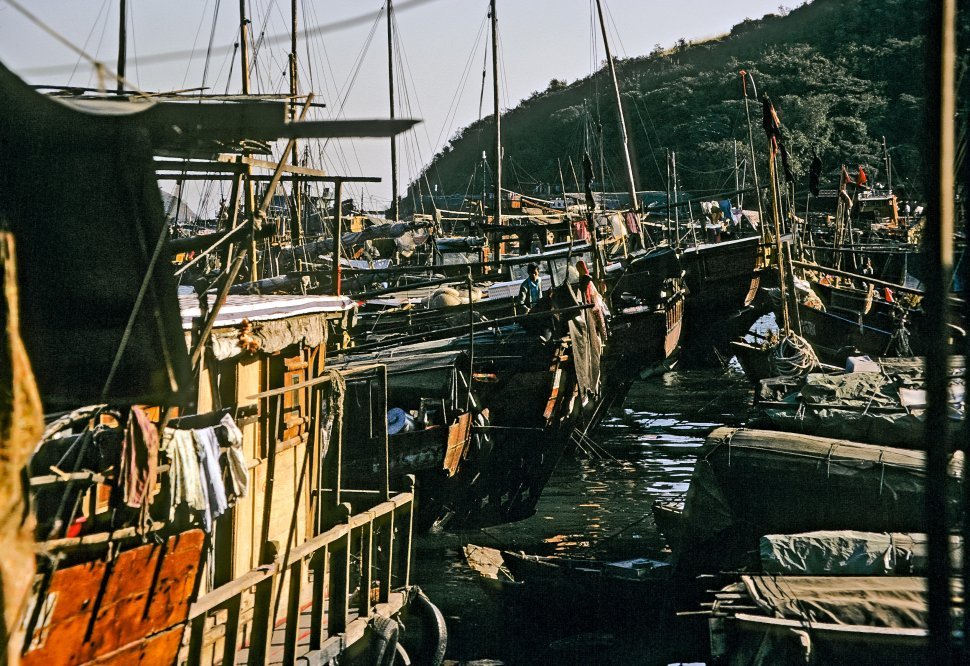 Free image of Fisherman standing on the back of his fishing boat in the harbor, circa 1974, Hong Kong, China