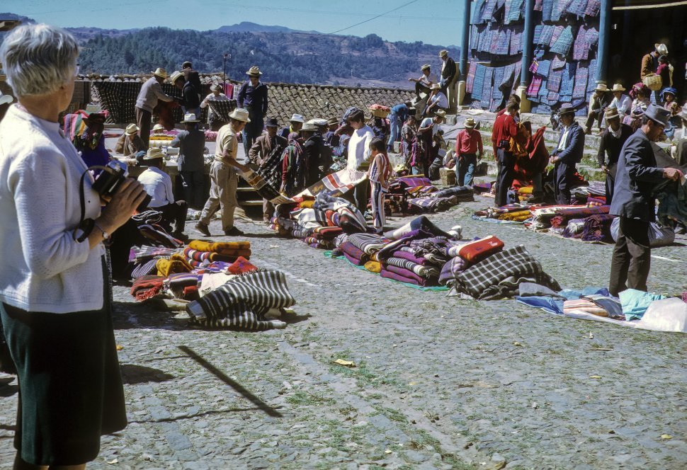 Free image of Woman tourist photographing locals selling their goods in the marketplace, Chichicastenango, Guatemala