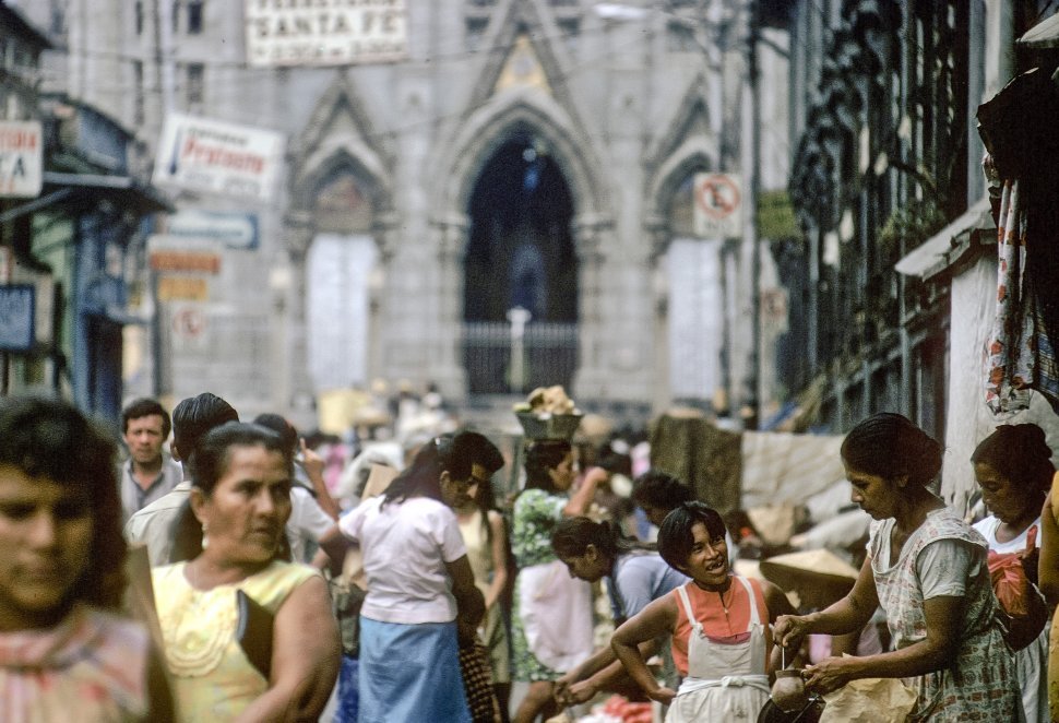 Free image of Woman balancing a basket on her head while walking through a busy marketplace, San Salvador