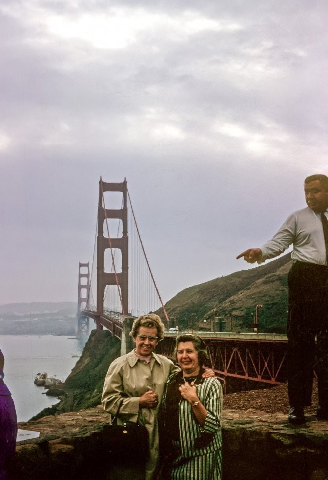Free image of Two women posing in front of the Golden Gate Bridge, and other tourists at a lookout point, San Francisico, California, USA