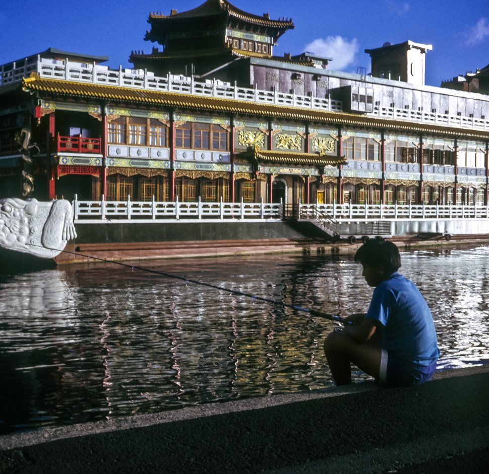 Free image of Young boy fishing next to a canal and palace, Asia