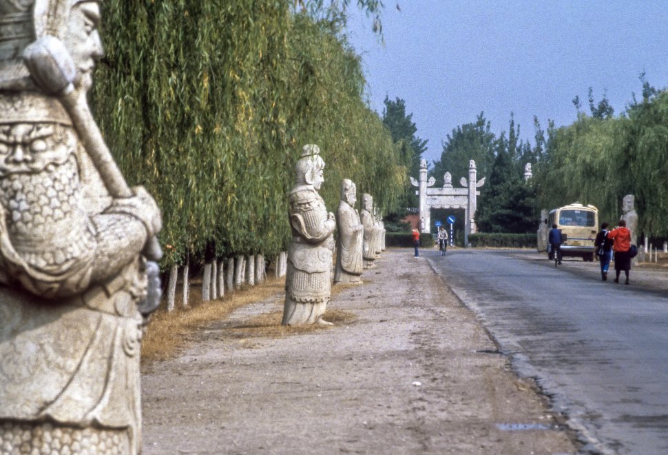 Free image of Large stone carvings of Chinese warriors and tourists walking towards park entrance, China
