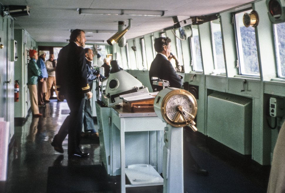Free image of Three sailors steering a cruise ship while tourists watch.