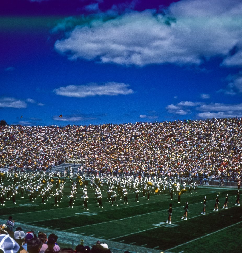 Free image of Crowded stadium of fans watching a marching band performing before a football game, USA