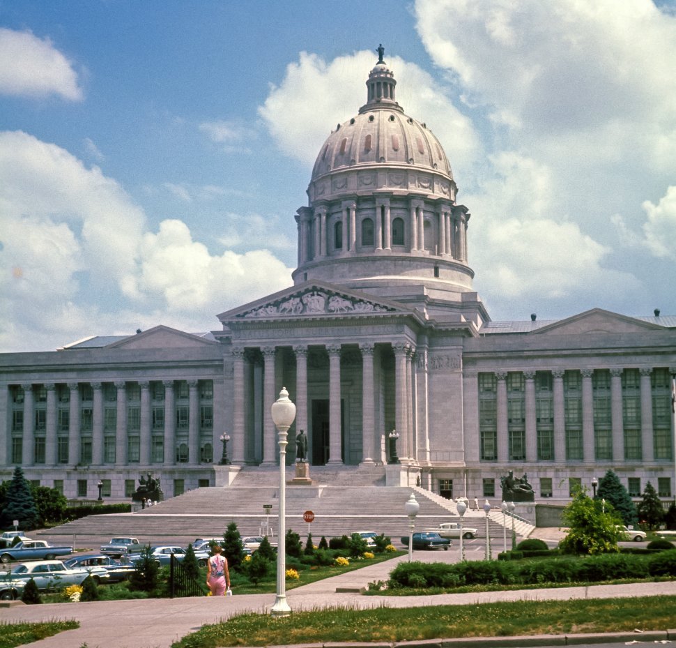 Free image of Woman walking in front of the The Missouri State Capitol, Jefferson City, MO. USA