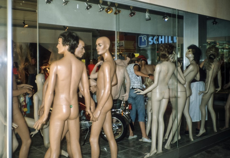 Free image of Woman posing mannequins in a shop window.