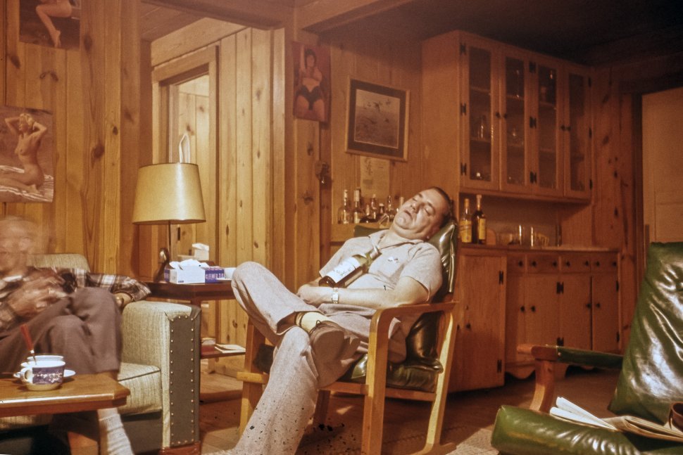 Free image of Humorous picture of a man passed out in a chair with a bottle on his chest, USA