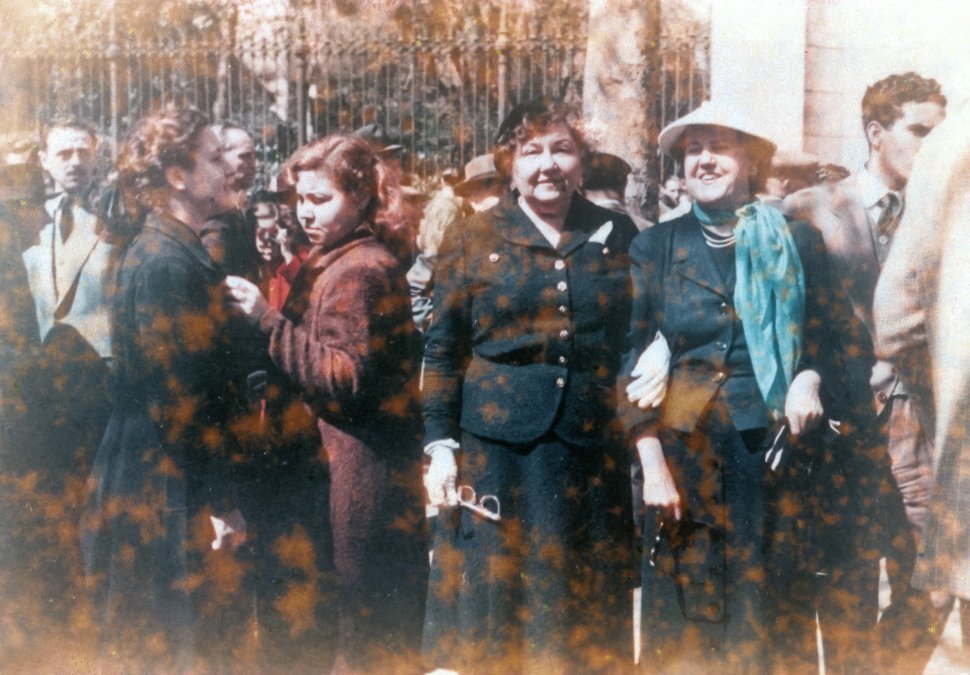 Free image of Weathered portrait of four women in their dress clothes standing at the edge of a crowd.