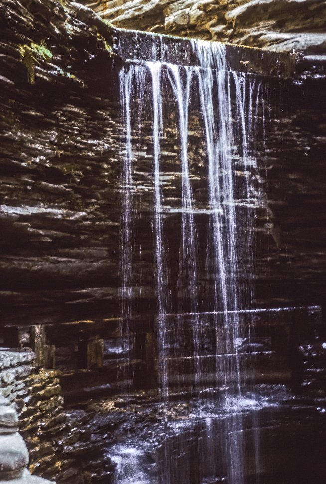 Free image of Small waterfall flowing down sandstone canyon walls.